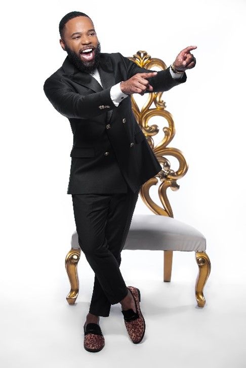 A man in a suit in front of a white and gold chair